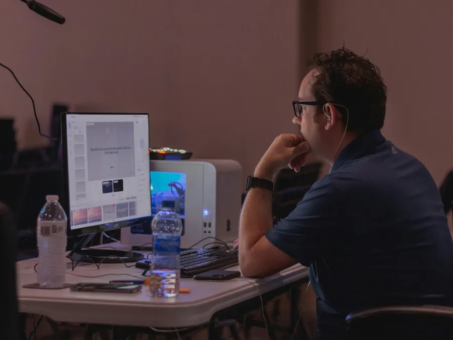 A solo volunteer at a desktop computer on a folding table, running Verse Copilot